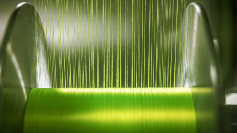 Green and yellow warp threads running through a textile machine.